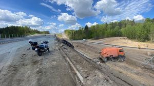 W tle na drodze stoi policyjny motocykl, obok po prawej stronie skarpa na na jej dole dwie ciężarówki