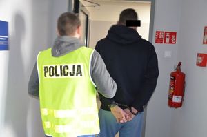 Policjant prowadzi zatrzymanego.