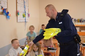 Policjant rozdaje kamizelki odblaskowe w klasie