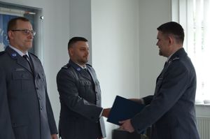 Dwaj policjanci stoją jeden obok drugiego, na przeciwko nich stoi Komendant Powiatowy, który gratuluje mężczyźnie stojącemu po prawej stronie zdjęcia (Zastępcy Komendanta Komisariatu Policji w Rumi).