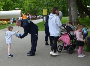 Park miejski - policjant częstuje dziecko cukierkami