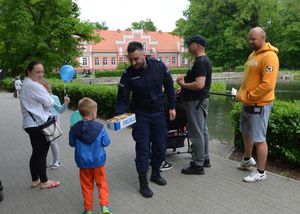 policjanci rozdają dzieciom w obecności ich opiekunów cukierki i odblaski