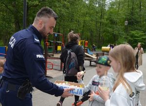 policjanci rozdają dzieciom w obecności ich opiekunów cukierki i odblaski