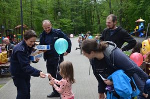 policjanci rozdają dzieciom w obecności ich opiekunów cukierki i odblaski