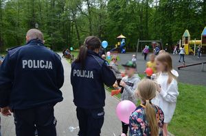 policjanci rozdają dzieciom w obecności ich opiekunów cukierki i odblaski