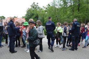 policjanci rozdają dzieciom w obecności ich opiekunów cukierki i odblaski