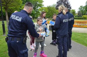 policjanci rozdają dzieciom w obecności ich opiekunów cukierki i odblaski