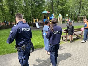 policjanci rozdają dzieciom w obecności ich opiekunów cukierki i odblaski