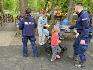 policjanci rozdają dzieciom w obecności ich opiekunów cukierki i odblaski