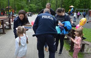 policjanci rozdają dzieciom w obecności ich opiekunów cukierki i odblaski