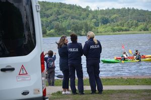 Policjantki rozmawiają z kobietą przy brzegu jeziora i pływających kajaków