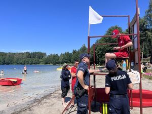 Policjanci na plaży rozmawiają z ratownikiem