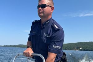 Policjant płynie jeziorem motorówką