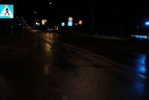 Noc, ciemna jezdnia, widoczny po prawej stronie bok radiowozu, w tle w oddali widoczny inny samochód który zatrzymał się po prawej stronie.
