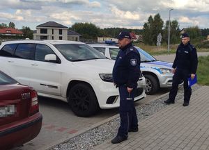 Policjanci stoją przy samochodzie, który został zabezpieczony.