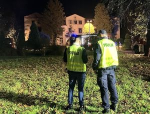 Policjanci stoją i rozmawiają. W tle widoczny jest budynek ośrodka.