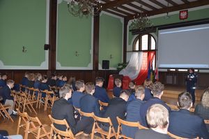 Policjantka prowadzi spotkanie, w tle widoczna prezentacja multimedialna.