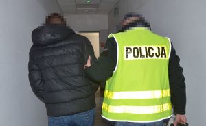 Policjant prowadzi zatrzymanego mężczyznę