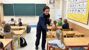 Policjantka podchodzi do ławek dziecięcych i rozdaje odblaski.