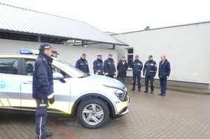 Policjanci i goście stoją przy radiowozie.