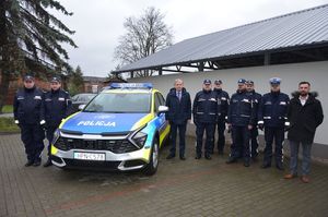 Przy radiowozie zdjęcie pozowane policjantów oraz gości.