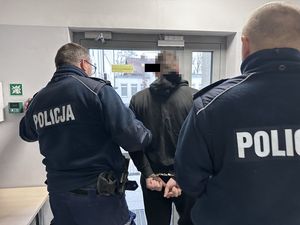 Policjanci wyprowadzają zatrzymanego mężczyznę