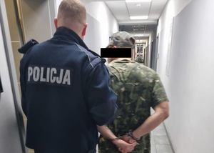 Policjant prowadzi zatrzymanego mężczyznę