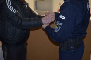 Policjant zakłada kajdanki zatrzymanemu