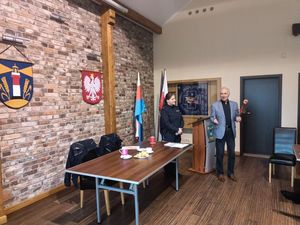 Spotkanie prowadzone przez policjantkę, uczestnicy siedzą przy stole konferencyjnym w Urzędzie Gminy w Choczewie.