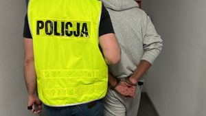 Policjant prowadzi zatrzymanego mężczyznę korytarzem komendy