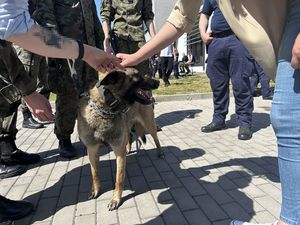 Uczestnicy wydarzenia głaszczą psa.