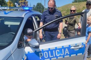 Policjant prezentuje dzieciom policyjny radiowóz