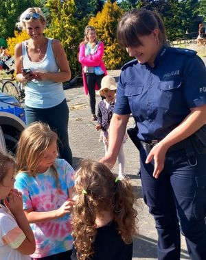 Policjantka wręcza dzieciom upominki.