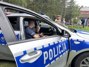 Policjant siedzi z dzieckiem w radiowozie