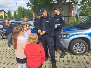 Policjanci przy szkole rozdają dzieciom odblaski.