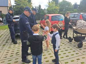 Policjanci przy szkole rozdają dzieciom odblaski.