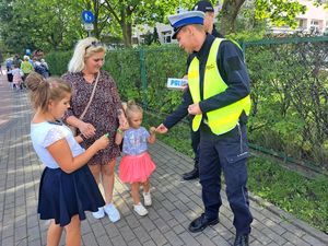 Policjanci przy szkole rozdają dzieciom odblaski.