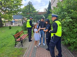 Policjanci przy szkole rozdają dzieciom odblaski.