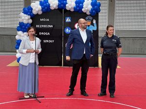 Przemawia dyrektor szkoły, obok niej stoi policjantka i dalej mężczyzna.