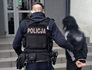 Policjant wprowadza zatrzymaną do komendy