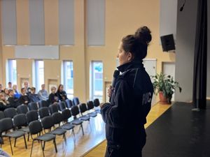 Policjantka stoi na scenie sali konferencyjnej i prowadzi spotkanie z młodzieżą.