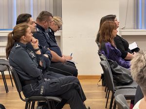 Komendant Powiatowy Policji w Wejherowie siedzi obok naczelnika prewencji, za nim siedzi dzielnicowy a następnie funkcjonariusz pionu dochodzeniowo - śledczego.