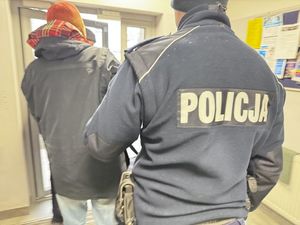 Policjant wyprowadza zatrzymanego z komendy.