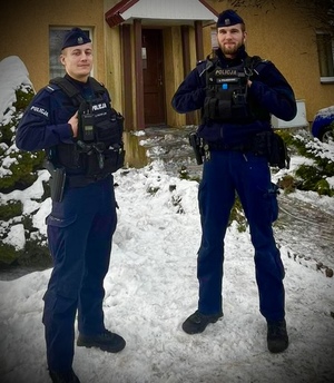 Dwóch policjantów stoi przed domem.