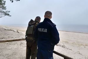 Policjant razem ze strażnikiem leśnym rozglądają się w rejonie morskim