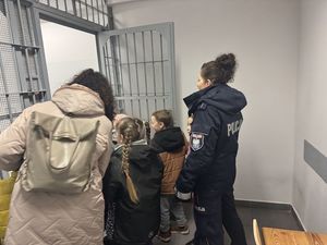 Policjanci rozmawiają z dziećmi, pokazują budynek KPP