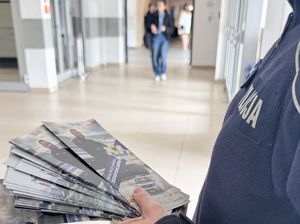 Policjantka trzyma w dłoni ulotki informacyjne