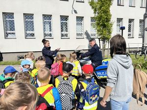 policjanci rozmawiają z dziećmi stoją przy policyjnym motocyklu