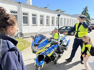 Policjanci stoją przy motocyklu a dziecko siedzi na motocyklu