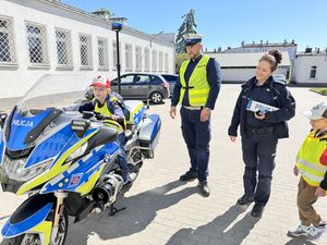 Dziecko siedzi na policyjnym motocyklu a policjanci stoją obok